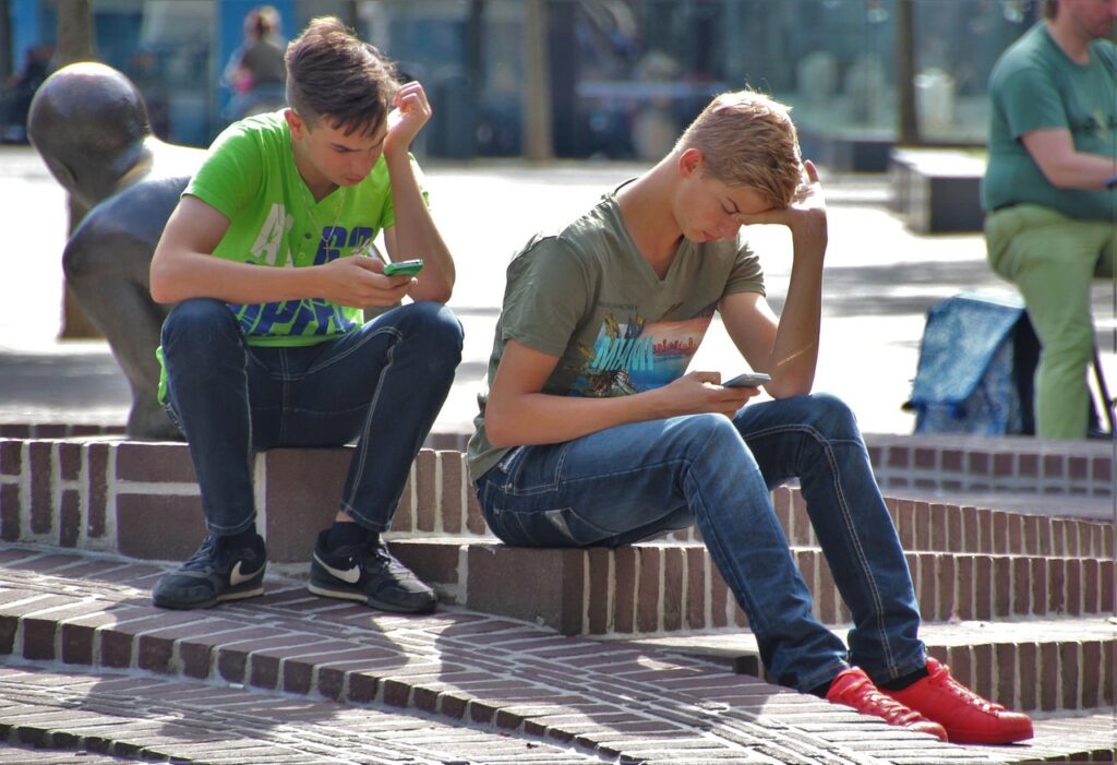 młodzi chłopcy pochyleni nad telefonem komórkowym